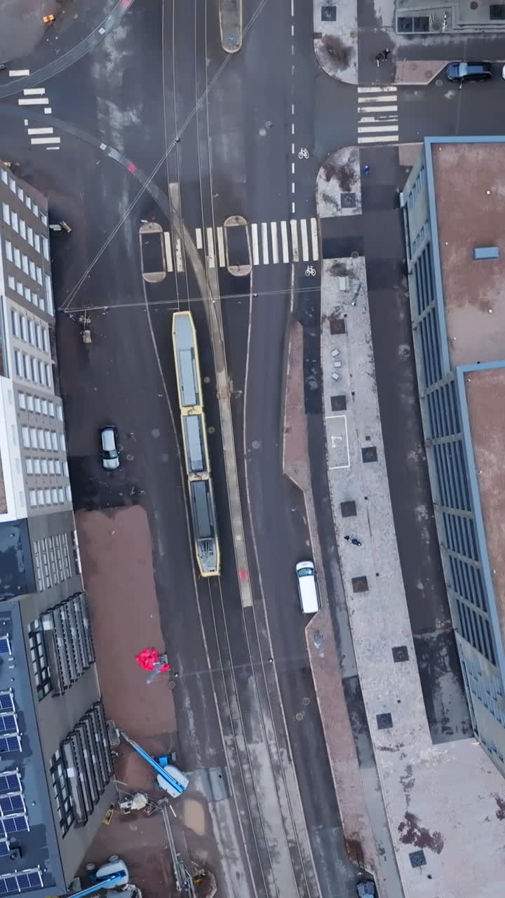 Vertical drone shot above a tram on the streets of Helsinki, cloudy day