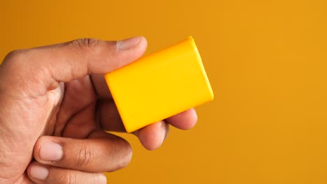 hand holding a yellow plastic box