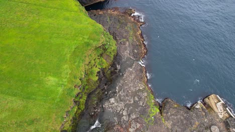 aerial view of mikladalur mossy cliffs and waterfall in the faroe islands