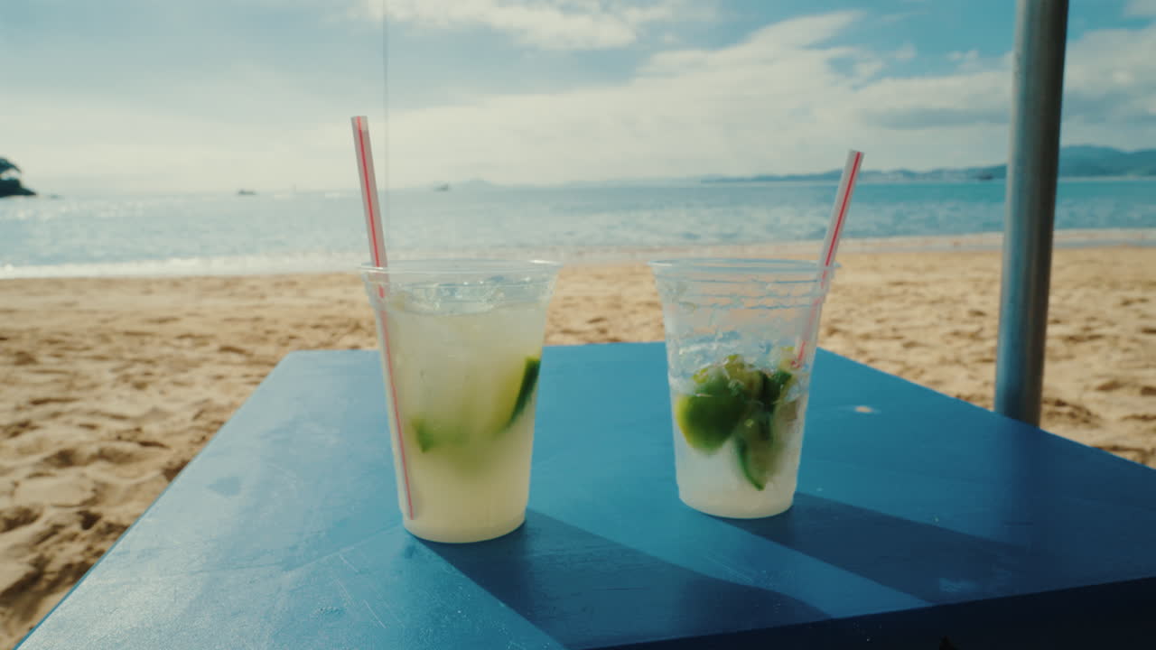 Two caipirinha cocktails on a table at a sandy beach in Brazil, close up still shot
