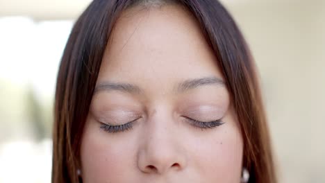 portrait close up of happy biracial woman with brown eyes and hair smiling, slow motion