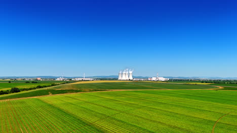 agricultural field in the picturesque countryside. modern industrial plant works at backdrop. aerial view.