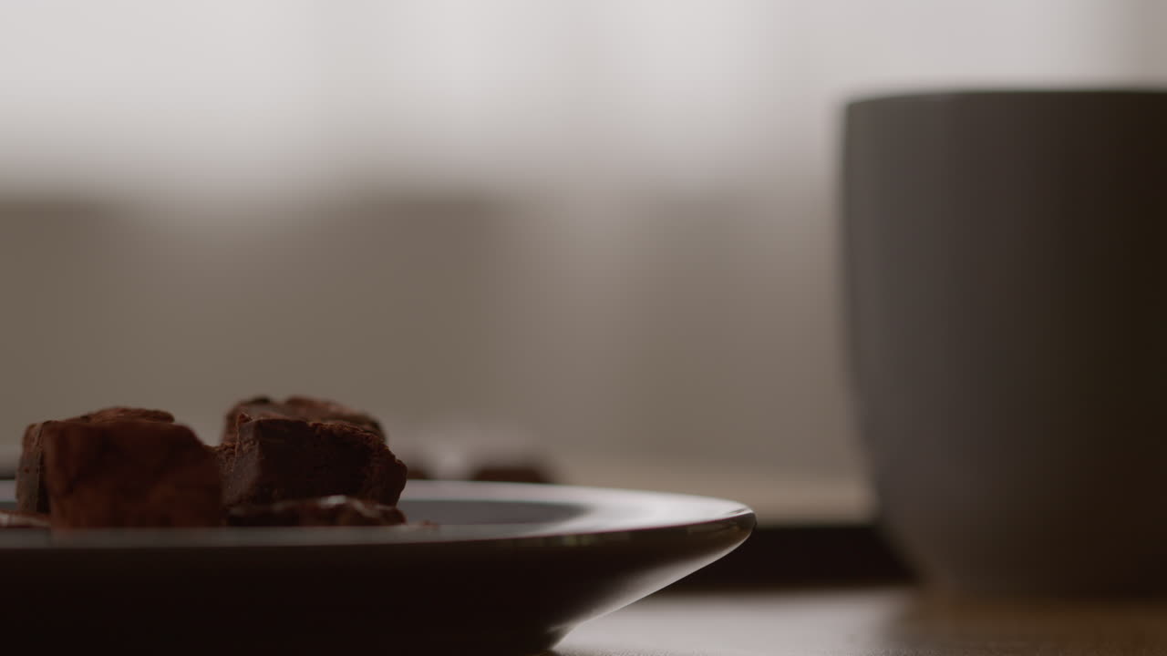 컵에서 뜨거운 음료를 마시는 사람의 에 초콜릿 브라우니의 접시를