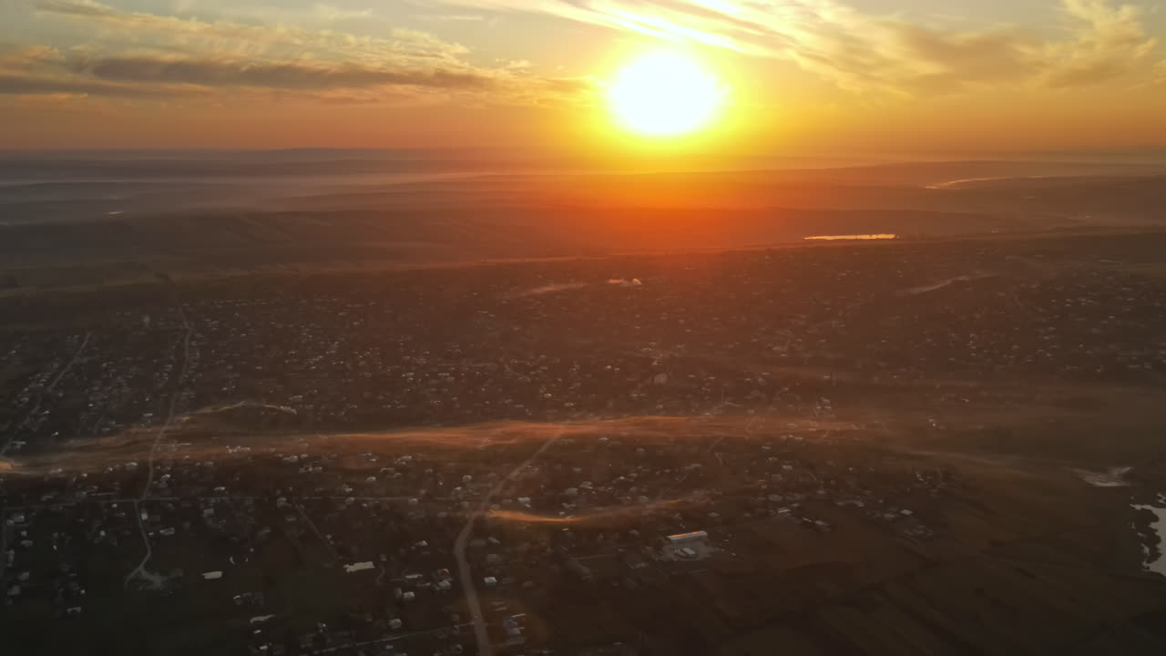 Aerial drone view of village in Moldova at sunset. Few columns of smoke from fires, wide fields