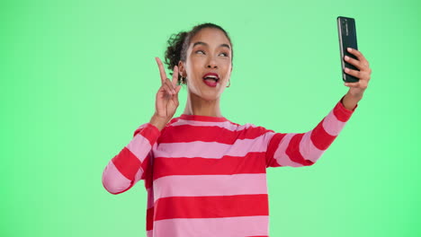 woman taking selfies in front of a green screen