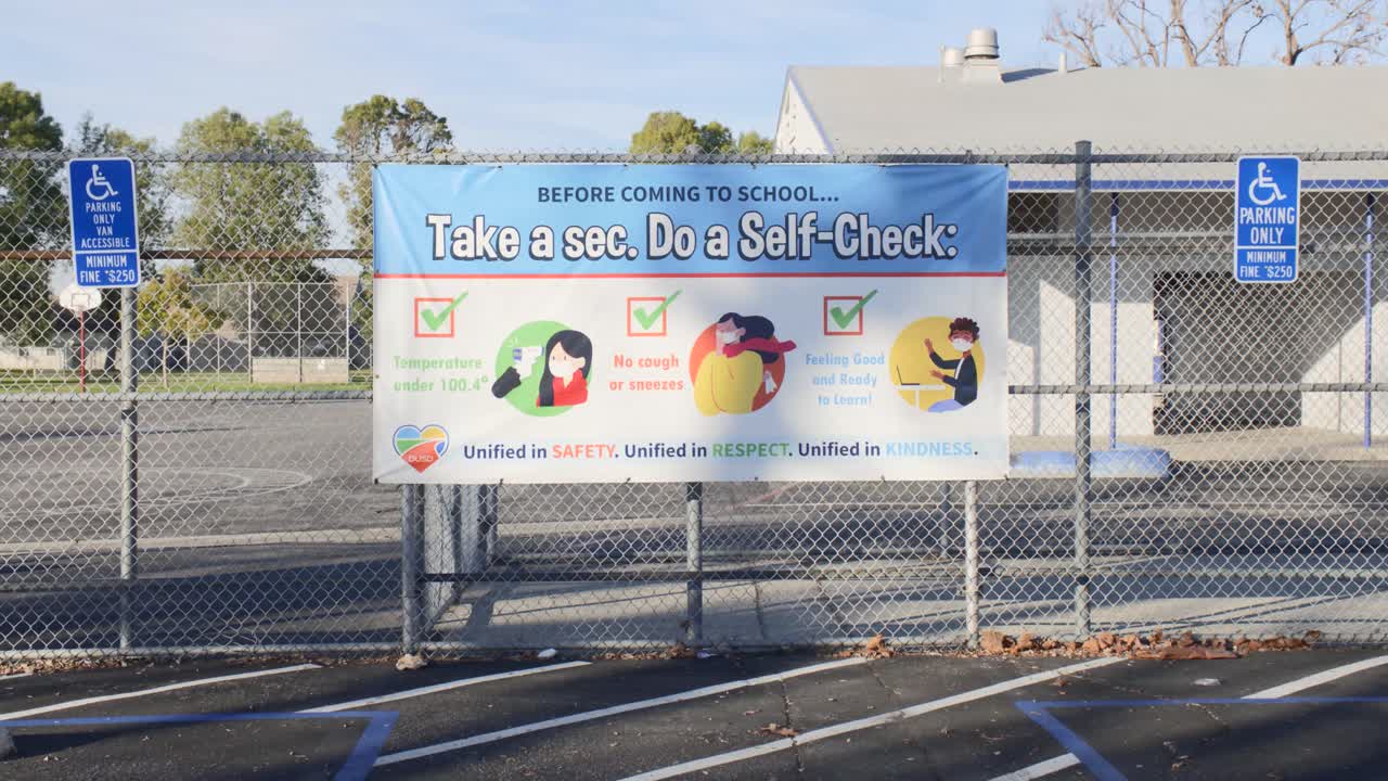 acérquese a un cartel de la lista de autocomprobación covid-19 fuera de una escuela primaria en un día soleado