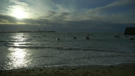 ominous storm clouds gathering over pier, beach and marina, december, cadiz, spain