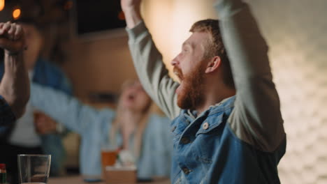 Close-up-of-a-group-of-male-and-female-friends-sitting-together-in-a-bar-and-watching-a-broadcast-on-TV-enjoying-a-goal-scored-shouting-and-hugging.-football-basketball-hockey