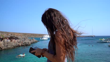 chica irreconocible enviando mensajes de texto en su teléfono inteligente cerca del mar