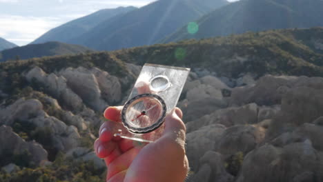 una mano de excursionista sosteniendo una brújula de supervivencia para encontrar el camino de regreso al campamento de manera segura en una situación de supervivencia después de perderse