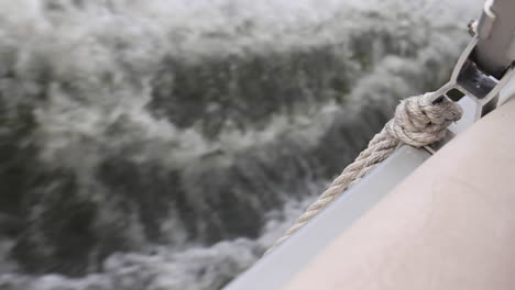 waves crash against boat with rope and buoy tied on the side