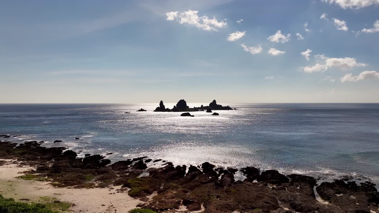 오키드 섬 의 바위 가 많은 해안선 과 바다 에  ⁇ 어 있는 바위 들 을 보여 주는 드론 의 전진 비행