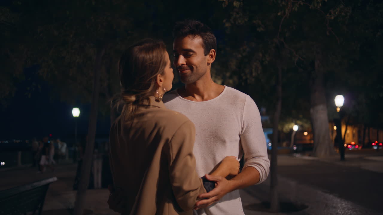 Persone sposate che si abbracciano per strada alla luce di un lampione. Una ragazza affettuosa si stringe all'uomo.