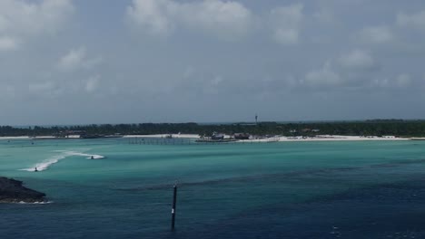 cruise ship pulling away from cay in bahamas, two jet skis race by