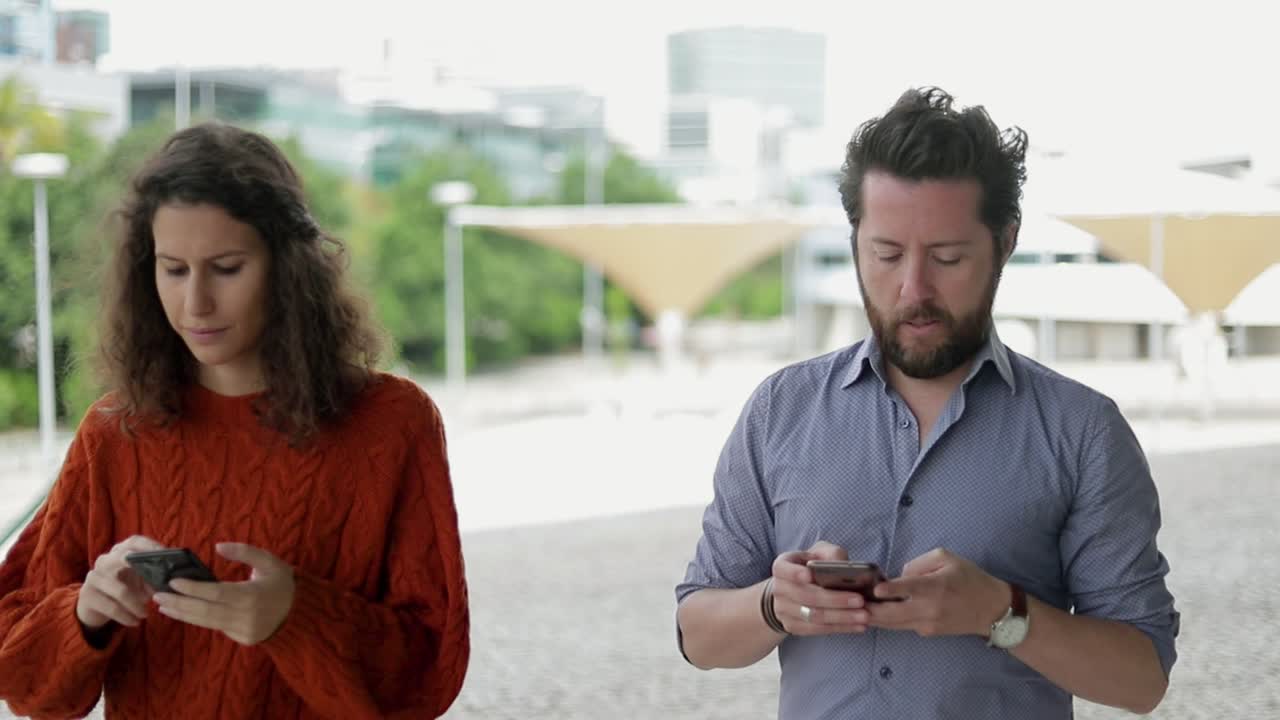 pareja enfocada usando teléfonos móviles al aire libre