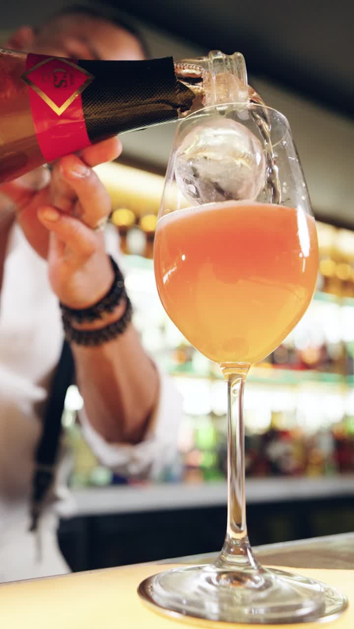 Barman che versa un cocktail frizzante in un bicchiere con ghiaccio