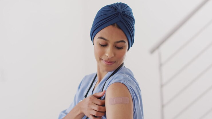 Video of happy biracial female doctor in hijab showing plaster after vaccination