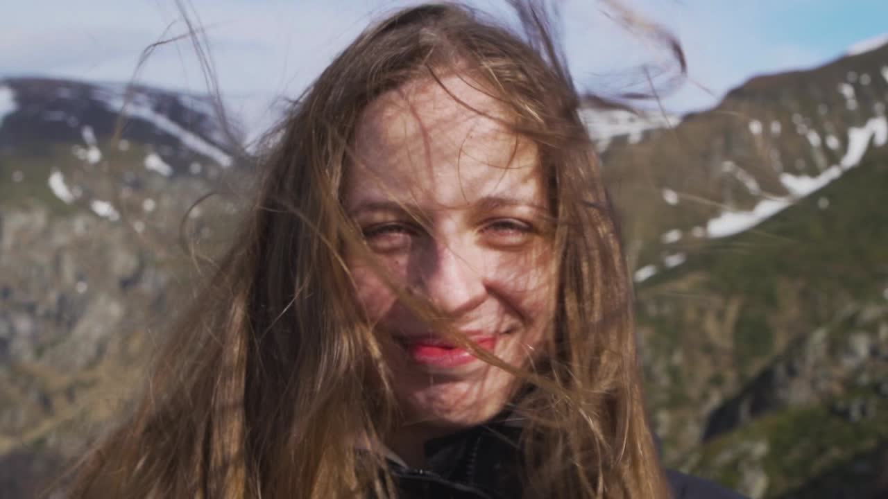 Slow motion shot of a woman enjoying the fresh wind atop Botev Peak, part of Bulgaria’s Stara Planina range. Her hair flows freely as she smiles, embodying joy and freedom in nature