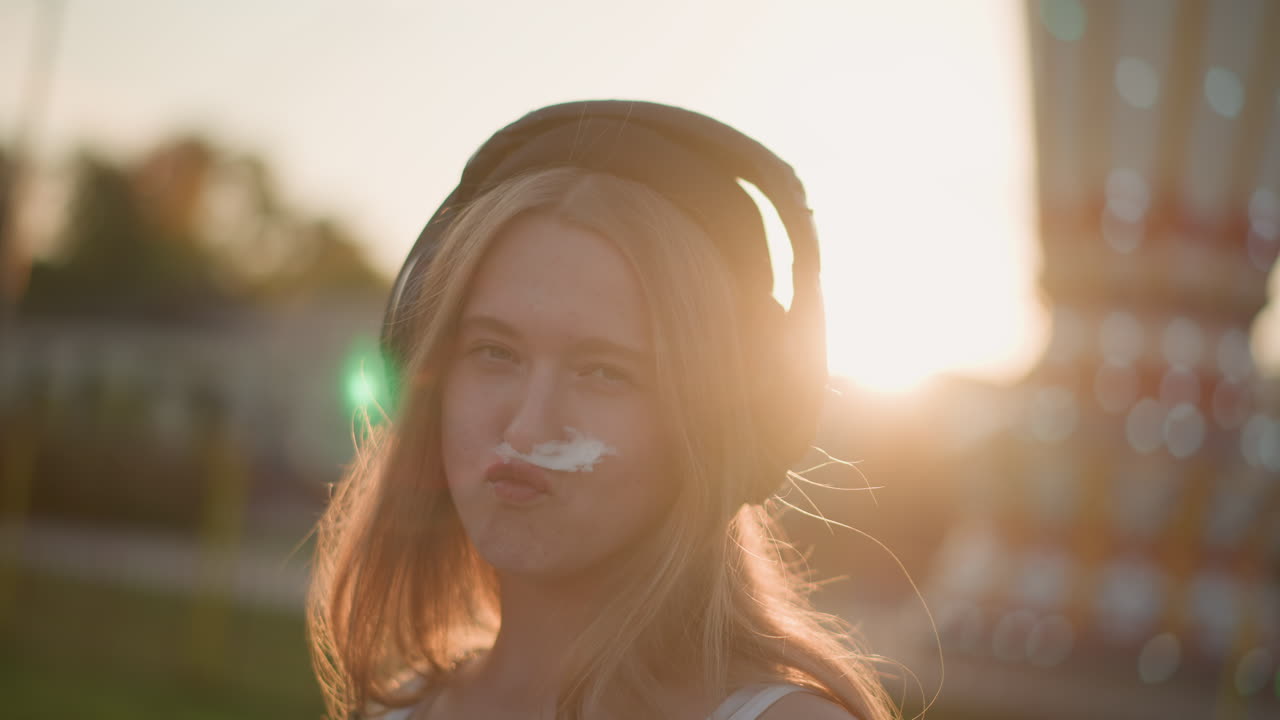 white girl with headphones golden hour lofi listener at fairground, backlit hair halo, carousel bokeh, contemplative expression, cotton candy hint, slow motion mood, indie summer vibe