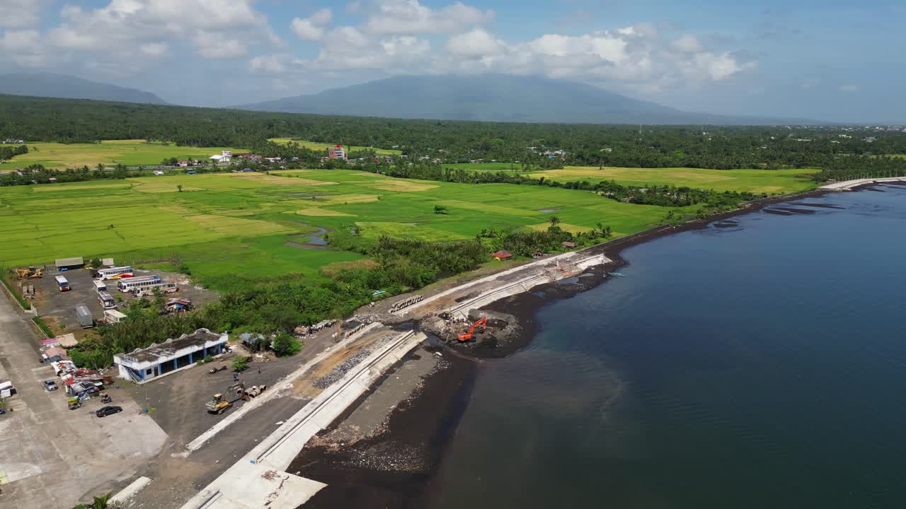 Orbiting aerial view of construction site along scenic Malilipot Seawall, Albay, Philippines.