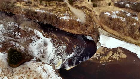 Aerial approaching view of partly frozen Jegala Waterfall, Estonia