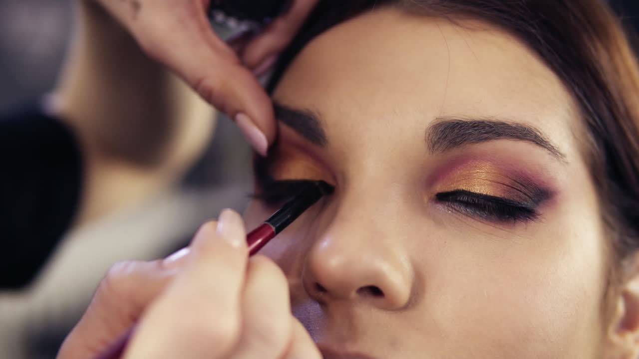 terminar el maquillaje de los ojos con humo aplicando delineador de ojos líquido negro en la línea superior de las pestañas.