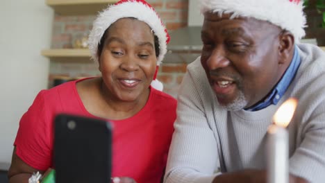 Feliz-Pareja-De-Ancianos-Afroamericanos-Con-Sombreros-De-Santa-Con-Regalos-En-Videollamada-En-Navidad