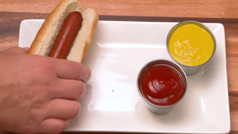 hand taking hot dogs off a plate