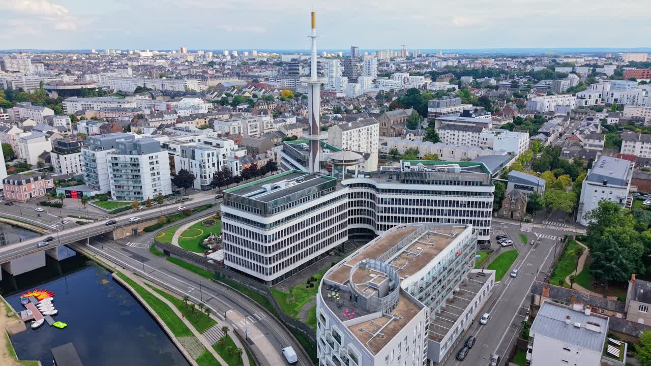 Drone advancing above Le Mabilais, showing the Vilaine, nearby roads with moving vehicles, surrounding buildings and the cityscape of Rennes