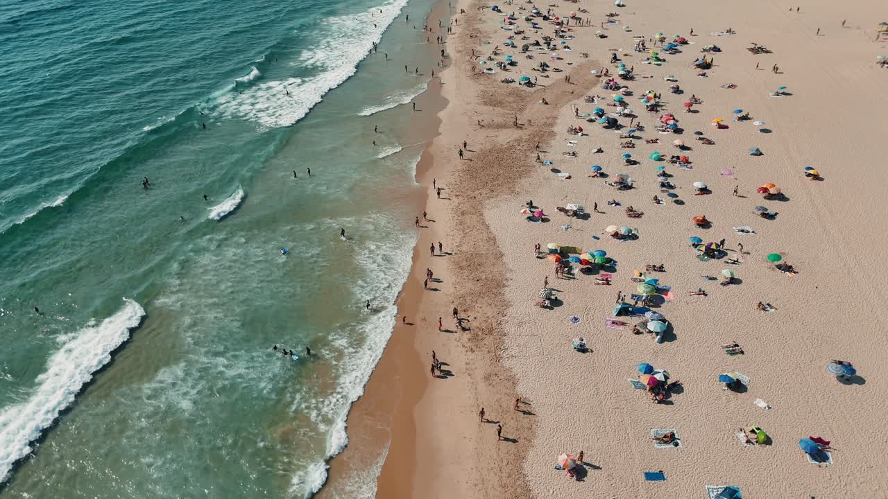 Aerial view of a crowded beach with people and umbrellas