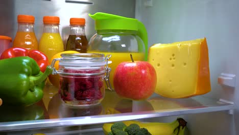 glass jar of fresh raspberries in a refrigerator