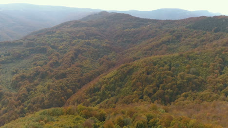 Aerial-footage,-mountains-and-woods-of-the-Balkan-Peninsula-during-autumn-with-typical-autumnal-reds,-greens-and-yellows