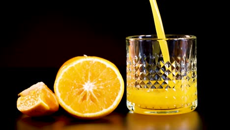 juice being poured into a glass with oranges