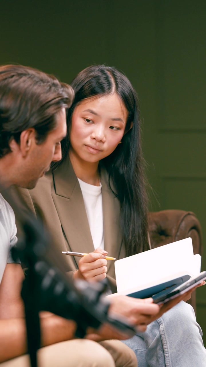 Young Professional Woman Taking Notes During Meeting with Colleague