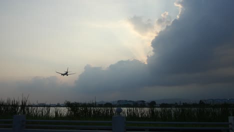 a commercial airplane approaches the airport for landing, gliding smoothly through the sky. the shot is taken from the riverbank,