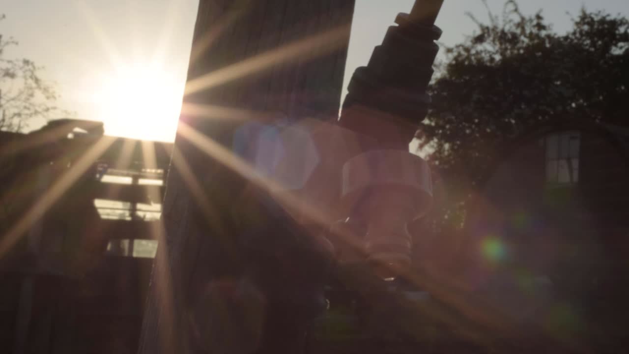 Dripping faucet tap in garden against sunset close up panning shot