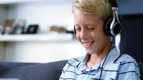 boy with headphones using laptop in living room