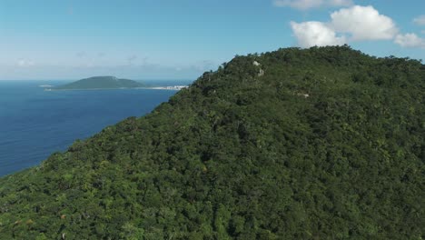 Emerging-from-behind-a-mountain-and-revealing-the-stunning-Ingleses-Beach-in-Florianopolis,-Brazil,-on-a-beautiful-sunny-day