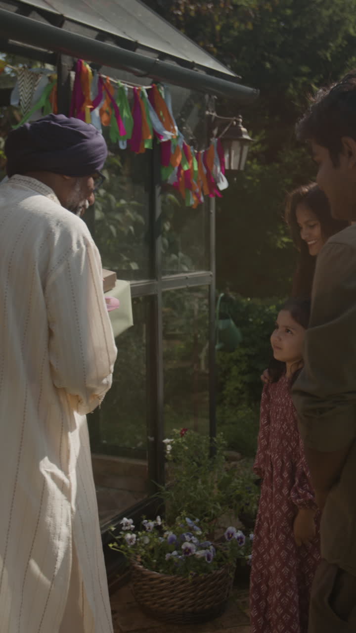 Multi-generational family celebrating outdoors with gift-giving and festive decorations