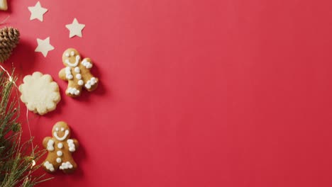 video of smiling gingerbread men with decorations over bright red background