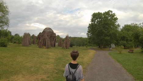 Girl-walks-toward-a-wooden-teepee-like-structure