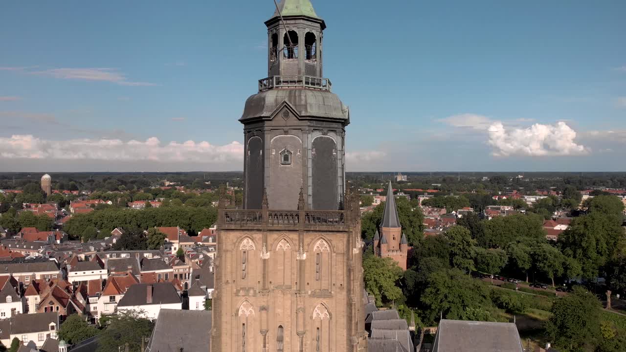 Closeup and approach aerial view of tower of the Walburgiskerk cathedral in medieval Hanseatic town of Zutphen in The Netherlands with the Drogenapstoren and wider town cityscape in the background