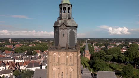 closeup and approach aerial view of tower of the walburgiskerk cathedral in medieval hanseatic town of zutphen in the netherlands with the drogenapstoren and wider town cityscape in the background