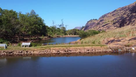 tranquil indian lake surrounded by green forest, rocky hills and clear blue sky. peaceful tourist destination for nature lovers, eco-tourists and travellers seeking serene landscapes in india