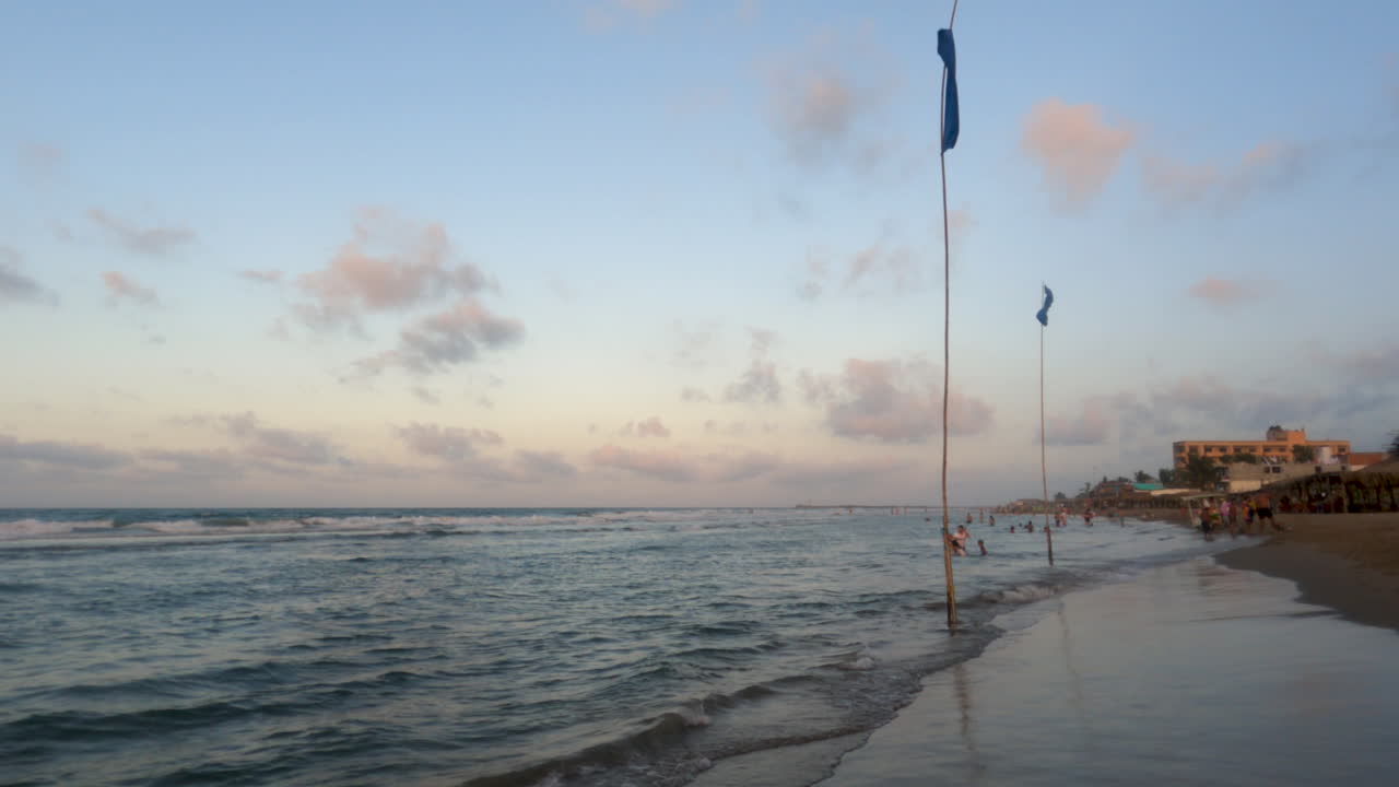 A beautiful sunset on a beach with life saving flags in place to ensure beachgoers safety. Flapping gently in the wind.