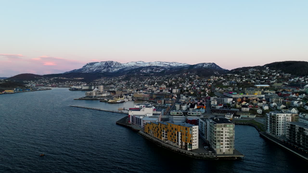 Harstad city, harbor, and waterfront at sunset, snow-capped mountains and beautiful arctic landscape in northern Norway. Aerial drone