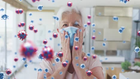 Animation-of-covid-19-cells-over-senior-caucasian-woman-in-face-mask