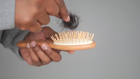 man holding hair brush with hair on it