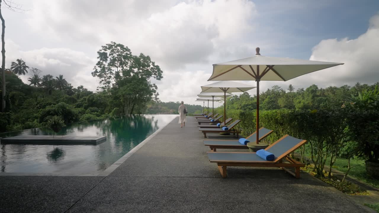 빈 리조트에서 수영장을 산책하는 럭셔리 라이프 스타일을 살고 흰색 커버 업 드레스에 금발 여자