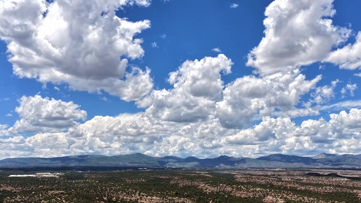 Timelapse 4K UHD con dron de una toma panorámica sobre una vasta cordillera y mesetas. Nubes que se mueven rápidamente muestran el clima dinámico y árido a través del extenso y accidentado paisaje